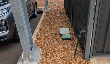 Wood chip mulch installation around poles and garden bed at a Palmerston property.